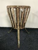 A cast iron cylindrical bin on tripod legs