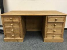 A large pine twin pedestal desk fitted with eight drawers