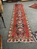 A fringed wool Persian runner on red ground