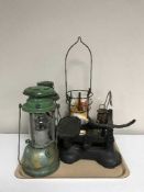 A tray of Tilley lamps and vintage cast iron scales