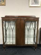 A mahogany shaped fronted display cabinet on claw and ball feet