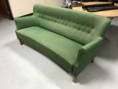 A mid 20th century shaped back settee in green button fabric