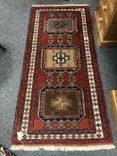 A fringed wool Eastern rug on red ground
