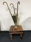 A brass stick stand in the form of an upturned umbrella containing three walking sticks and a pine