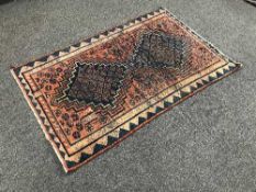 An Eastern wool carpet of geometric deign on red ground