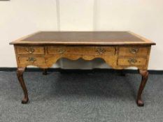 An antique walnut writing desk with brown inset panel top on claw feet