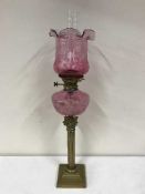 A brass Corinthian column oil lamp with pink glass shade, Hinks Lever No.