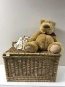 A wicker storage seat containing Christmas decorations together with a teddy bear,