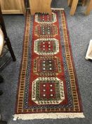 A fringed Persian geometric design rug on red ground 212 cm x 80 cm
