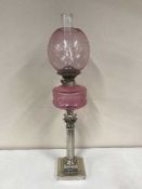 A Victorian Corinthian column oil lamp with pink glass shade