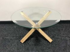 A circular glass topped coffee table on oak base