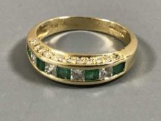 An 18ct gold emerald and diamond half eternity ring