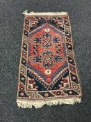 A fringed woollen rug of geometric design on brown ground