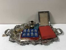 A large silver plated twin handled serving tray containing perfume bottles, part cruet sets,