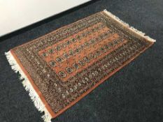 A fringed Afghan rug on peach ground