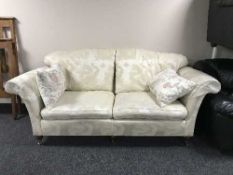 A two seater settee in cream fabric depicting dragons