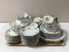 A tray containing two Victorian china tea services decorated with flowers