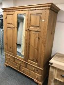 A pine triple door wardrobe fitted with five drawers below