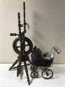 A vintage spinning wheel and Victorian style miniature pram with doll