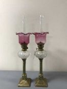 A pair of Victorian brass and cranberry glass oil lamps,