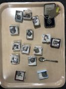 A tray containing fifteen silver fobs in boxes together with a silver teaspoon