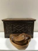 A pine box with carved oak panel containing wooden bowls,