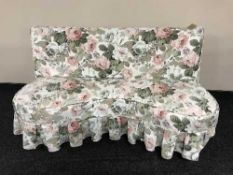 An upholstered kidney shaped settee on mahogany legs