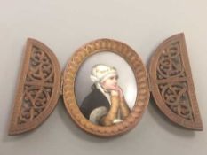 An antique wooden framed painted porcelain plaque depicting a young girl