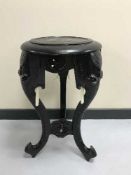 An ebonised plant stand with elephant trunk supports