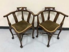 A pair of mahogany corner armchairs on claw and ball feet