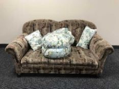 An early 20th century three piece suite upholstered in brown floral fabric