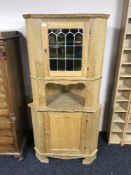 A blonde oak corner cabinet with stained leaded glass door