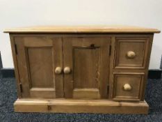 A pine TV stand fitted cupboard and drawers beneath
