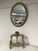 An oval gilt framed mirror and an ornate metal photo frame