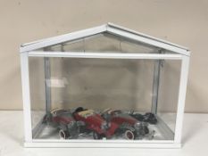 A glass display case containing three Classic die cast cars and a motor bike,