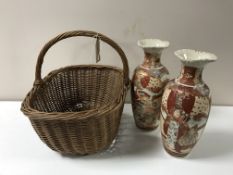 A wicker hand basket containing a pair of Japanese Satsuma vases