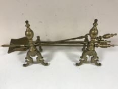 A pair of brass fire dogs and a companion set