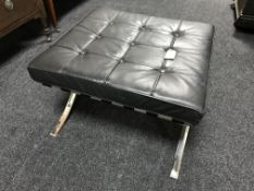 A black button leather footstool on chrome X frame support