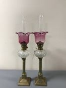 A pair of Victorian brass and cranberry glass oil lamps,