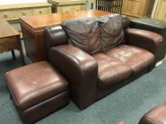 A pair of brown leather two-seater settees with matching footstool