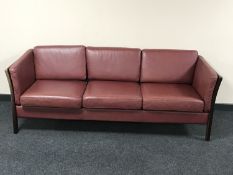 A late 20th century Danish wood framed three seater settee with burgundy leather cushions