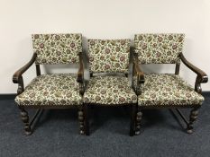 A pair of carved oak armchairs in tapestry fabric and a single chair