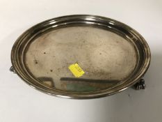 A circular silver card tray on paw feet, width 20.