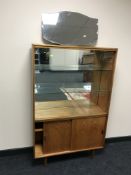 A teak sliding door bookcase and an unframed mirror