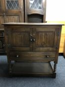 A Chapmans Siesta oak double door linen fold cabinet fitted a drawer