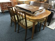 A mid 20th century extending table with three leaves and four chairs