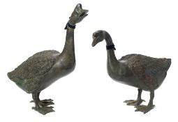 A pair of life-sized bronze geese: both standing, one looking upward, 53cm and 67cm. high.