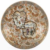 A massive Japanese Satsuma porcelain dish: decorated with two shaped panels of ladies on a garden