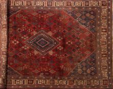 A Joshagan carpet:, the brick red field with a central indigo stepped lozenge pole medallion,