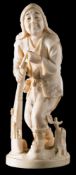 A Japanese carved ivory okimono of a hunter: leaning on his matchlock gun smoking a pipe,